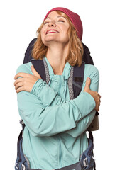 Middle-aged Caucasian woman with hiking gear hugs, smiling carefree and happy.