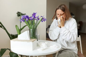 Sick young woman suffering from allergy, fever or flu blows nose and sneezing in paper tissues,...