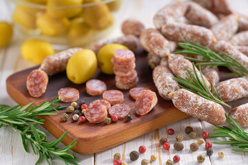 chorizo mini, spicy pork fermented dry cured salami sausages with spices and olives  on a wooden table.