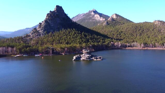 An aerial view of the fascinating nature of Borovoye, the huge Okzhetpes rock and stunning views of the turquoise Lake Burabay and the stone island of Zhumbaktas surrounded by coniferous trees.