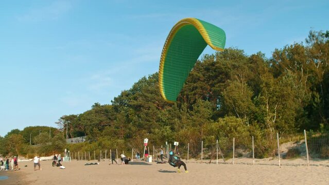 A paraglider is preparing to take off on a sandy beach in summer. Gdansk. Paragliding in Poland over the Baltic Sea against a clear blue sky