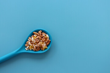 A mixture of air flakes in a blue spoon on a blue background. Puffed oatmeal, quinoa, rice and corn flakes