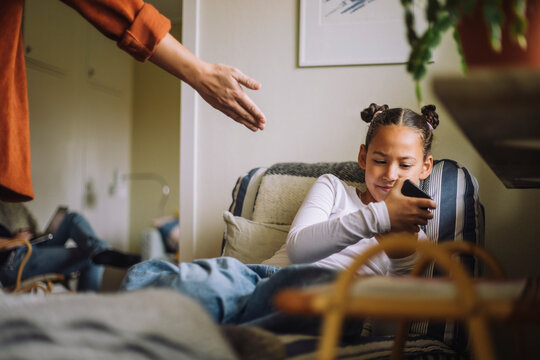 Daughter ignoring father while using mobile phone at home