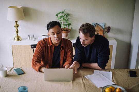 High angle view of gay couple discussing over laptop while working from home