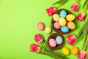 Fototapeta na wymiar Easter eggs with a bouquet of tulips on a bright background. Easter celebration concept. Colorful easter handmade decorated Easter eggs. Place for text. Copy space.