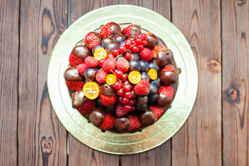 Rich chocolate cake decorated with sauce and fresh berries, strawberry, cherry, grape and blueberry