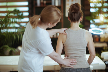 massage therapist checking clients back condition during checkup