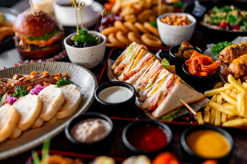 A delightful spread of food: sandwiches, sushi, and a burger, all beautifully presented. Perfect for a feast