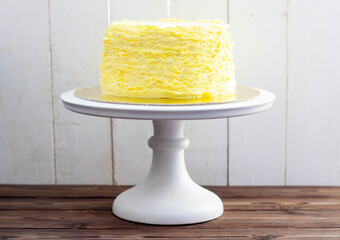 Yellow cake with fondant ruffles on rustic wooden background