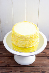 Yellow cake with fondant ruffles on rustic wooden background
