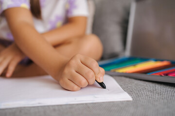 Close-up of little girl's hand with pencil. Five year old girl drawing at home after kindergarten. Black pencil