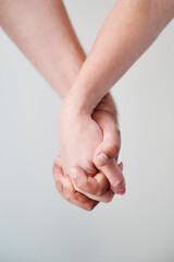 Two hands held together in grasp against neutral background. Close up of man's and woman's hand....