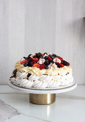 Pavlova cake with whipped cream cheese, chocolate sauce and fresh berries on grey background