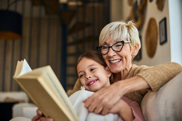 A lovely grandma and grandchild reading a funny book, smiling.