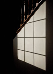 Light from a window outlining a window frame on a stairway wall