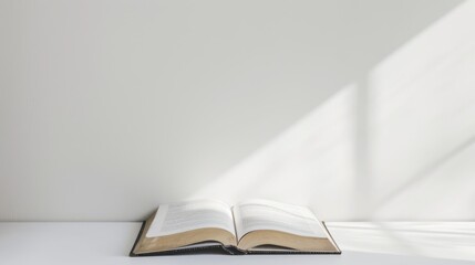 An open book placed on a clean, white desk with soft lighting