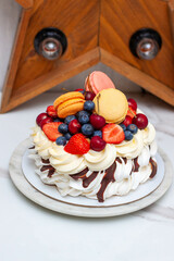 Pavlova cake with strawberry, raspberry, bluberry, macarons and chocolate sauce