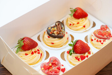 Juicy cupcakes for Valentine's day with strawberry, dipped into melted chocolate, chocolate hearts, red sprinkles in the shape of heart