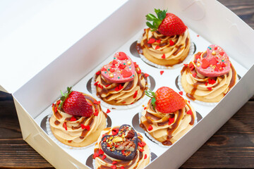 Juicy cupcakes for Valentine's day with strawberry, dipped into melted chocolate, chocolate hearts, red sprinkles in the shape of heart