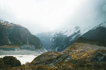 Fototapeta na wymiar Mountain Lake Landscape Under Cloudy Sky in the valley with Snow-Capped Peaks and Lush Green Valleys during a Summer Day at Mount Cook, New Zealand