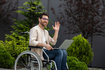 Young bearded man in a wheelchair working on laptop