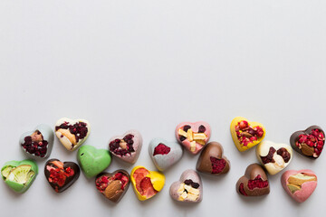 chocolate sweets in the form of a heart with fruits and nuts on a colored background. top view with space for text, holiday concept