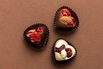 chocolate sweets in the form of a heart with fruits and nuts on a colored background. top view with space for text, holiday concept
