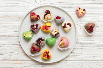 Plate with different chocolate on colored background. Assortment of fine chocolates top view vith copy space Health and obesity concept
