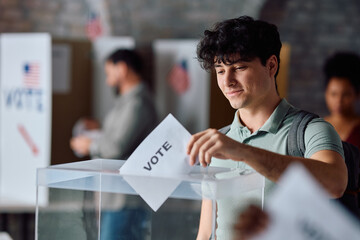 Young happy man voting at polling station during USA elections.