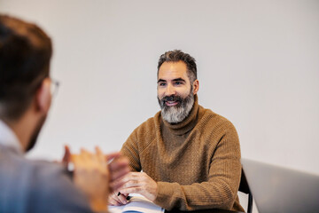 Portrait of happy senior manager on a meeting with coworkers in boardroom.