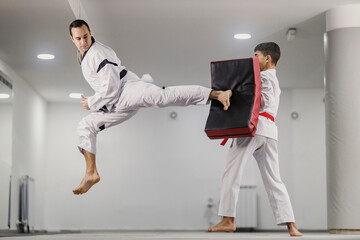 A taekwondo master is kicking a kick pad at martial art school.