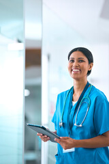 Portrait Of Female Doctor Or Nurse With Digital Tablet Checking Patient Notes In Hospital