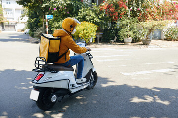 Delivery man in yellow uniform riding motorbike