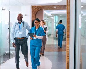 Busy Corridor In Modern Hospital With Male And Female Medical Staff