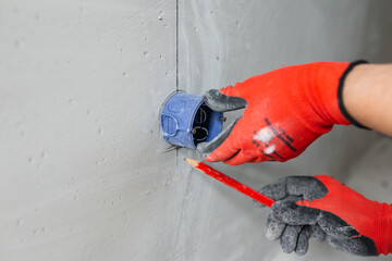 Dirty work of an electrician on electrical wiring - preparing a wall for hidden wiring and installing an electrical outlet