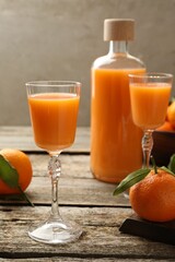 Delicious tangerine liqueur and fresh fruits on wooden table
