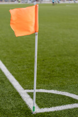 Fototapeta premium Orange corner flag on a plastic pipe - marking and equipment of a football field before the match