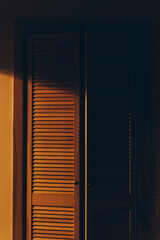 Mysterious shady wardrobe door illuminated by warm yellow lamp light. A concept of family secrets, crimes, truth, home invasion, and safety. - 750757883