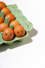 chicken eggs with painted faces on white background, vertical top view