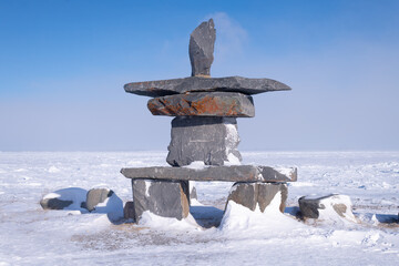 An Inukshuk (a manmade stone cairn used as a landmark) on the shore of Hudson Bay in Churchill, Manitoba, Canda in Winter.