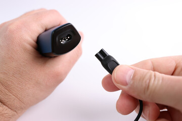 The clipper is connected to the power cable. The concept of household electrical appliances.