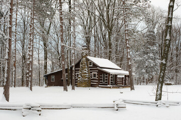 A cabin along the road in Brown County State Park. The ground and trees are covered in snow in the middle of winter in Indiana. 