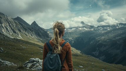A woman with long blonde hair is standing on a mountain top, looking out at the beautiful landscape - Powered by Adobe