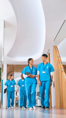 Multi Cultural Medical Team Wearing Scrubs Walking Along Corridor In Modern Hospital 