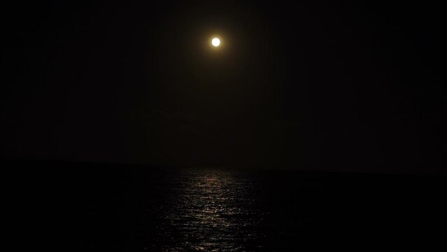 Supermoon shining brightly in the night sky reflecting off the surface of the Mediterranean Sea