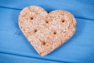 Fresh wholegrain bread in shape of heart for breakfast. Blue boards