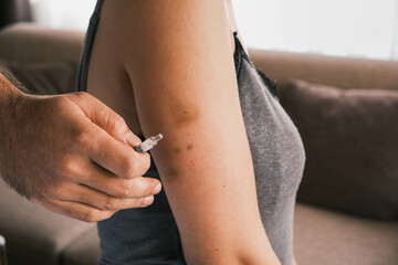 Closeup of giving an intramuscular anticoagulant injection into the arm using a safety syringe....