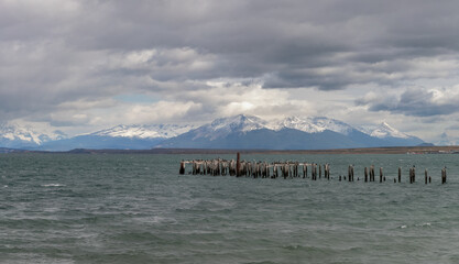 Old Pier Remnants Against a Majestic Snowy Mountain Range