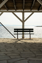 A bench on the seashore with a beautiful view of the open sea and the nearby island.