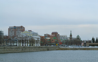 Naklejka premium A city landscape with a river and various buildings on a cloudy day